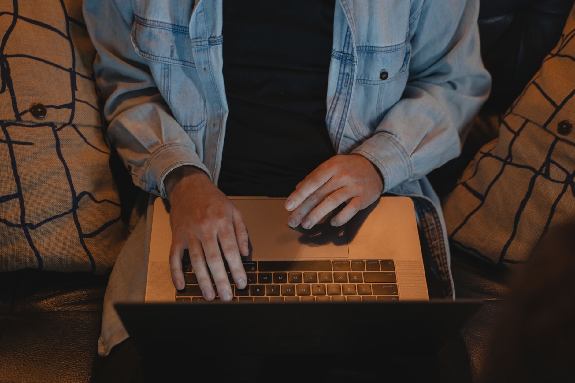 Nærbillede af en person, der skriver på en bærbar computer siddende indendørs.